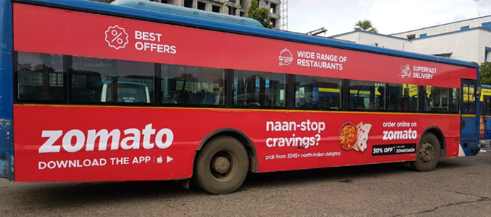 City bus fully wrapped with Zomato branding and food delivery promotional graphics