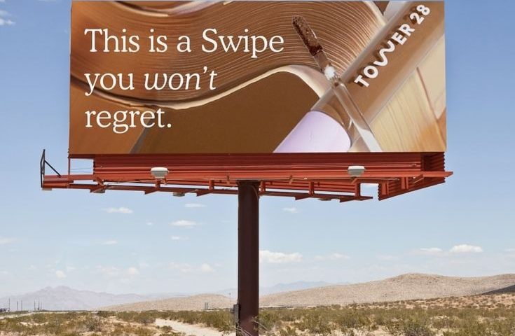 Tower 28 beauty billboard with “This is a swipe you won’t regret” messaging in desert outdoor advertising setting