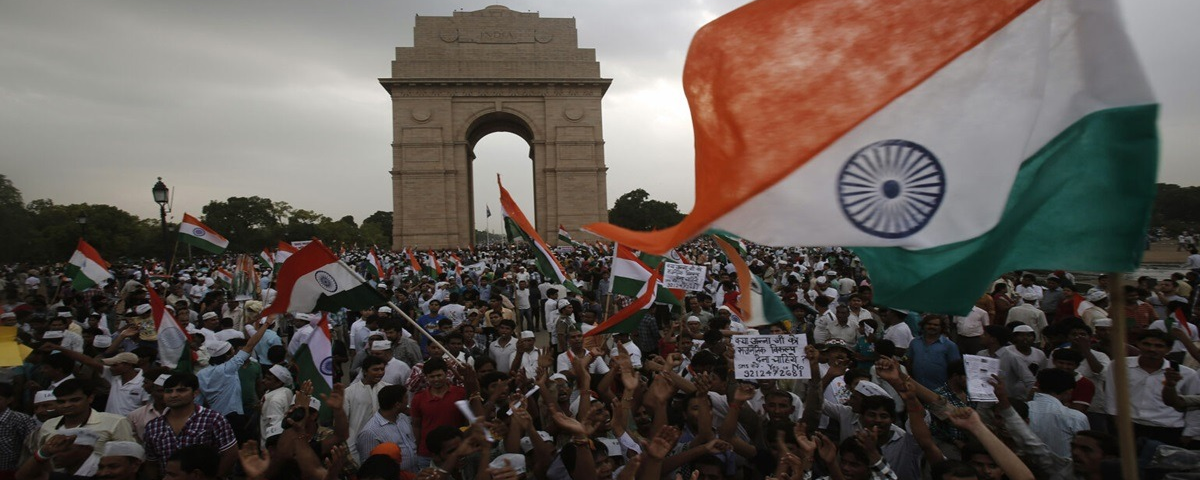 Large crowd of protesters waving Indian national flags at India Gate, New Delhi, during a public demonstration