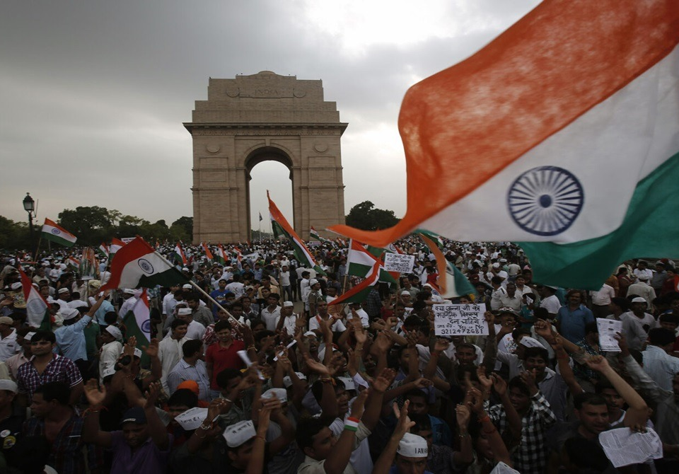 Large crowd of protesters waving Indian national flags at India Gate, New Delhi, during a public demonstration