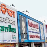 A streetside commercial building facade in Odisha featuring large multilingual storefront signage for Boyanika and Kalaniketan. The storefront displays bold branding in Odia and English with colorful exterior panels, fashion advertisements, and retail shop entrances along a busy urban road.
