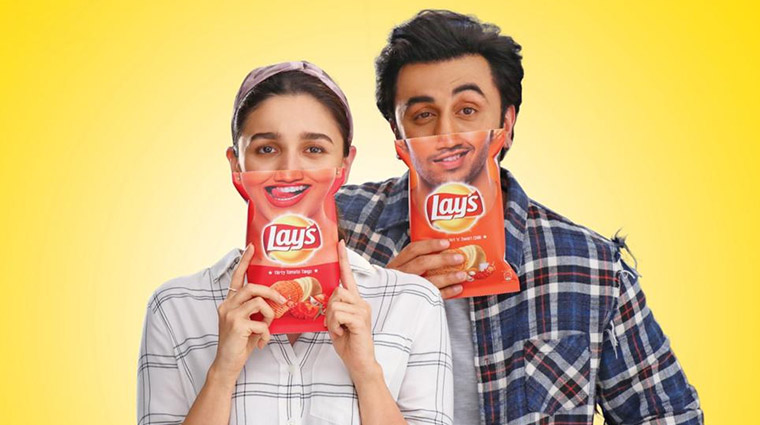This image shows the marketing campaigns by Lays India featuring Alia Bhatt and Ranbir Kapoor holding the chips packet