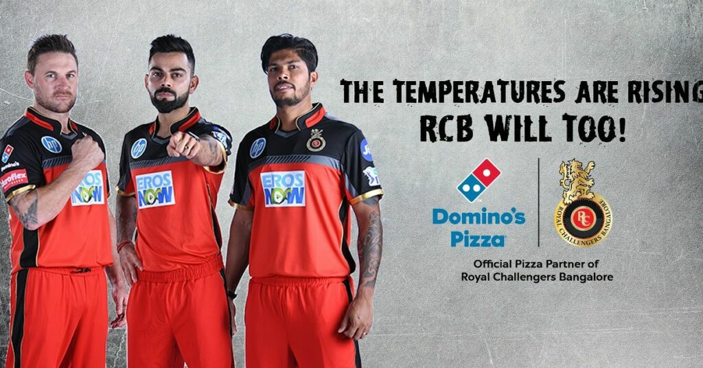 This image shows the partnership of Domino’s and RCB in the IPL with three cricketers standing 