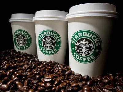 This image shows three white cups with Starbucks branding and coffee beans