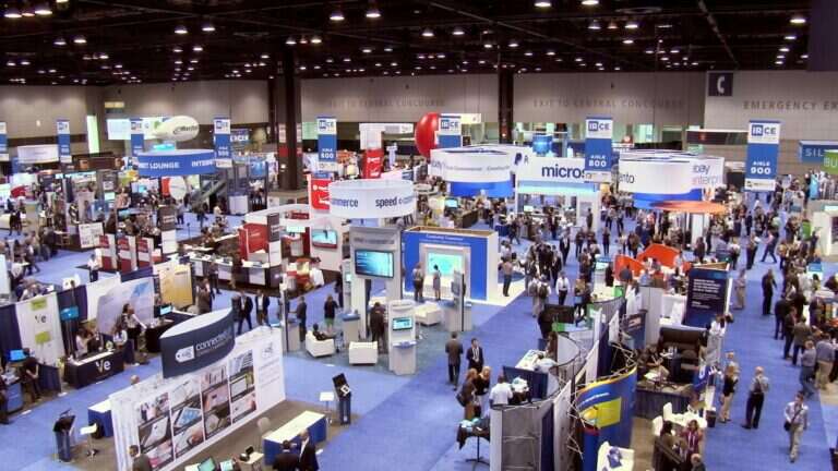 This image shows people around different company stalls engaging in a trade show