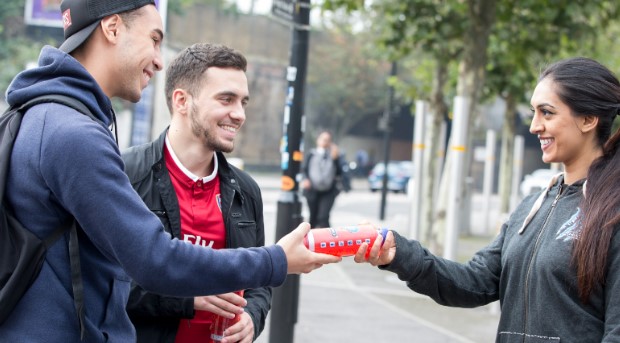 A picture showing offline marketing ideas for startups where a girl is promoting a brand and interacting with two boys
