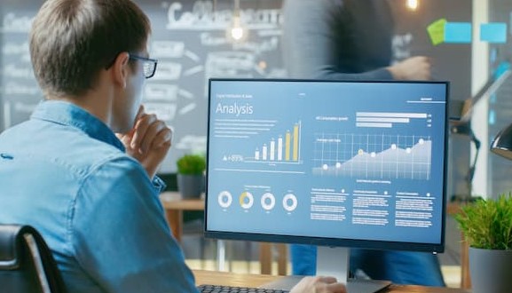 data analyst working in the office at two monitors in the evening