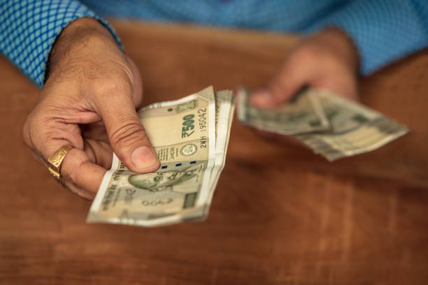 A man handing out some 500 rupee currency notes.
