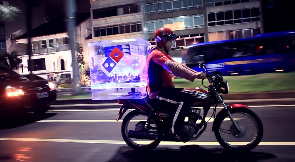 This image shows a person on a bike going for pizza delivery with pizza in a transparent box
