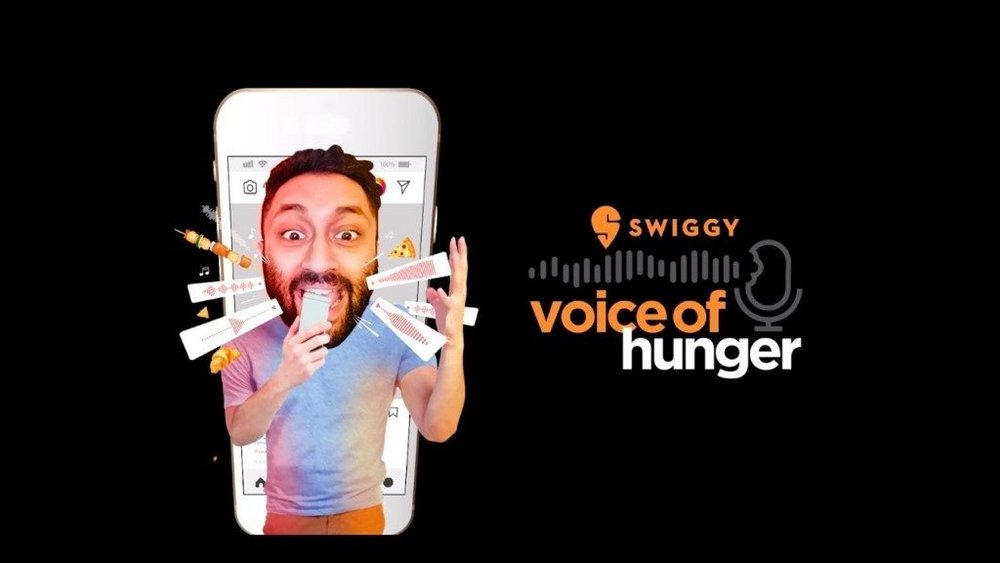 This image shows a man with a phone in hand recording a voice message as a part of the #VoiceOfHunger campaign by Swiggy