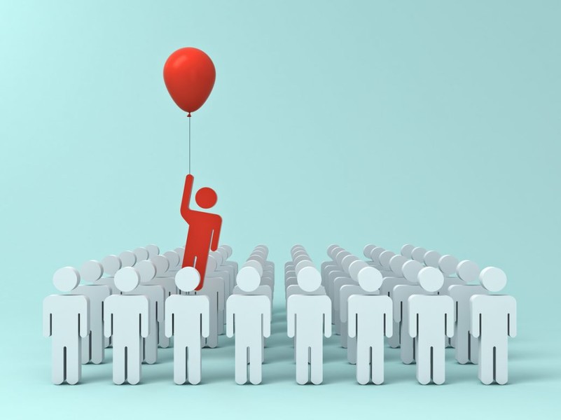 This image shows a person in red with a balloon in the air ahead of all the white people depicting competitive advantage