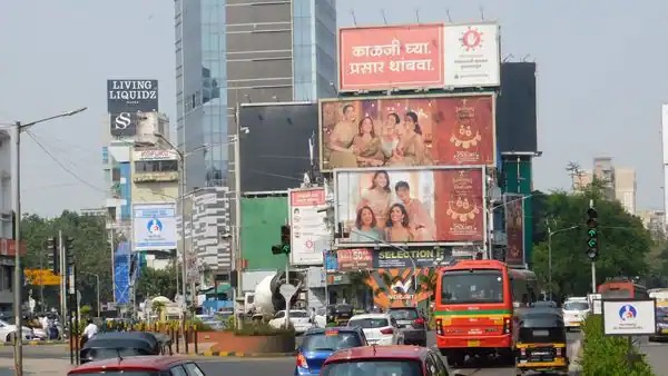 This image shows many hoardings and billboards at a cross-road with several vehicles passing by them