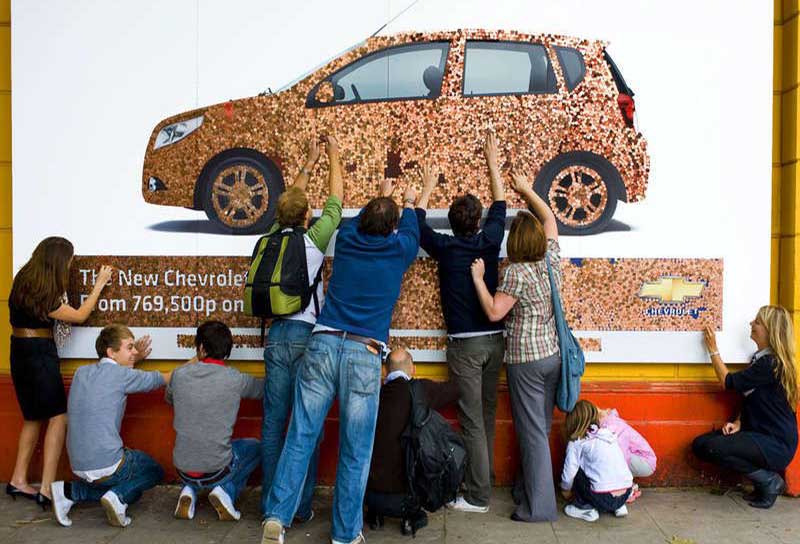 People collecting pennies from the Chevrolet billboard ad.