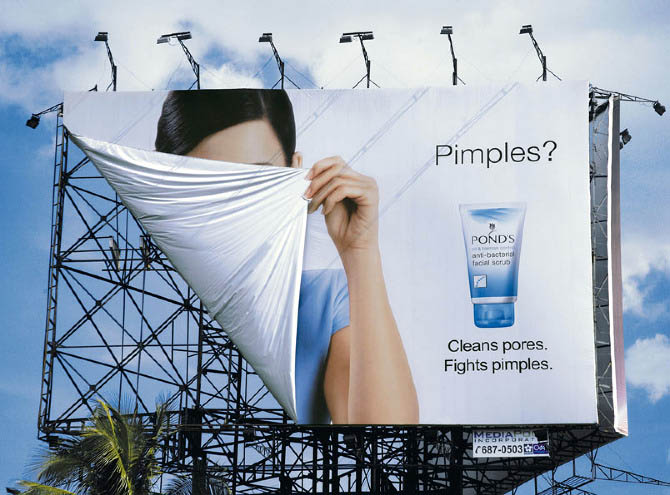 The girl in the billboard uses the billboard edge as a face cover.