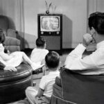 a family sitting together and watching advertisement in TV