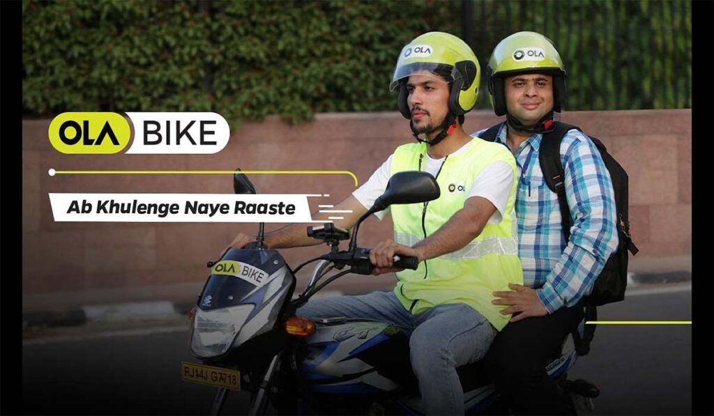 Two people wearing helmets and travelling on a bike. 
