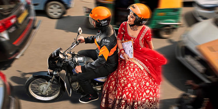 A bride sitting at the back of a motorcycle.