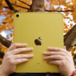 A person holding an Apple iPad air featuring the Apple logo.