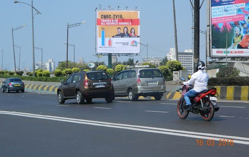 Large roadside billboard along a wide Mumbai highway visible across multiple lanes.