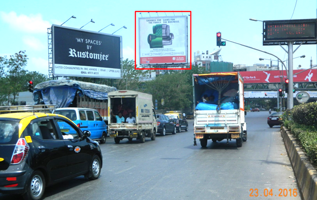Signal-facing hoarding at a major Mumbai road intersection with long red-light dwell time.