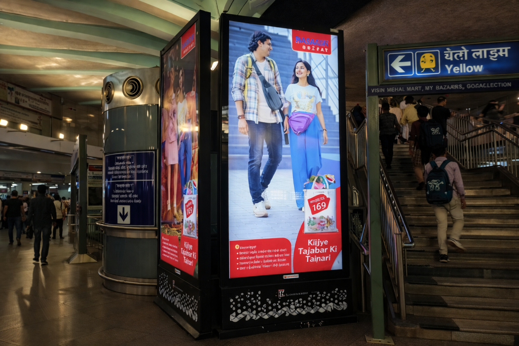 Digital advertising kiosk inside a metro station showing a couple in a fashion advertisement near stairs