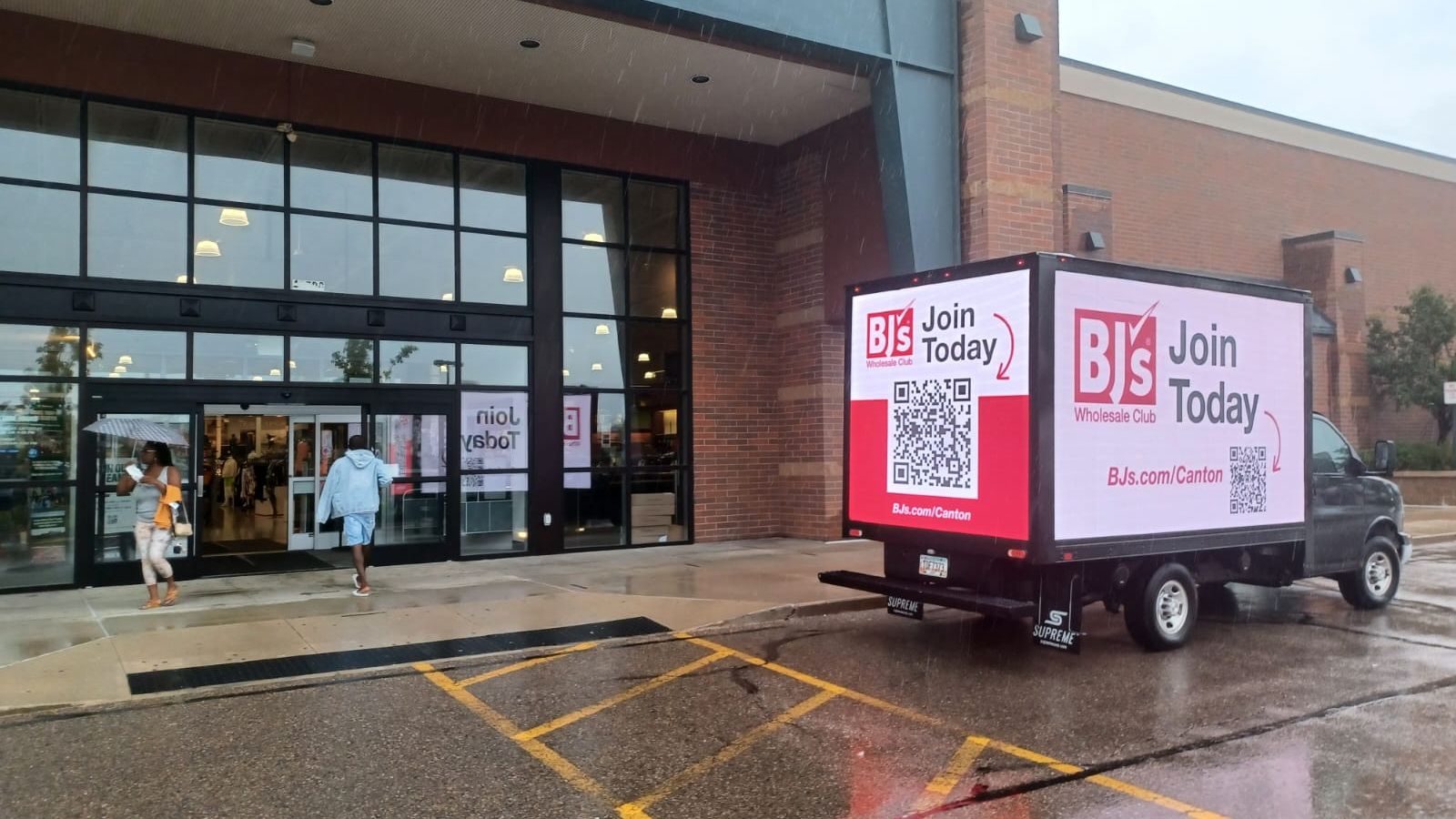 BJ’s Mobile Digital Billboard Activation Outside Retail Location BJ’s Wholesale Club mobile digital billboard truck parked outside a retail store entrance in rainy weather.