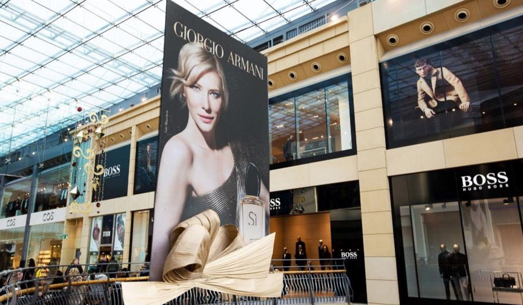 Large Giorgio Armani perfume advertisement display inside a shopping mall atrium