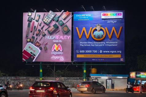 Illuminated Myntra and Vigos billboards displayed at night near traffic