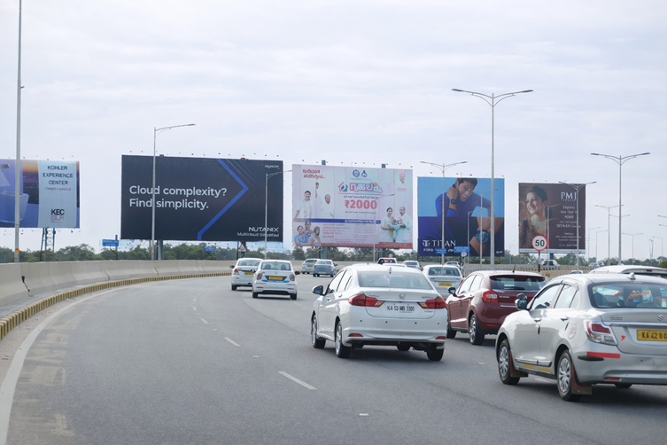 Multiple large-format billboards lining a curved highway with traffic