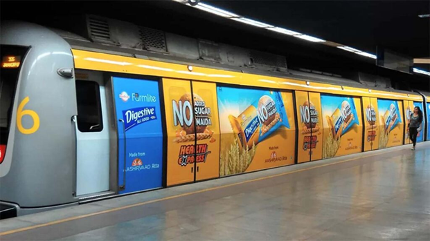 Metro train wrapped with Sunfeast Farmlite Digestive biscuit advertisements across multiple panels at a station platform.