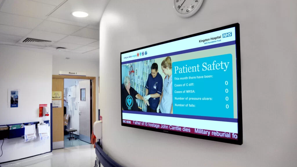 Hospital Digital Screen Showing Patient Safety Dashboard Wall-mounted digital screen in a hospital corridor displaying patient safety statistics and healthcare information.