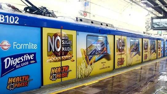 train exterior covered with Sunfeast Farmlite Digestive biscuit advertisements along the station platform.