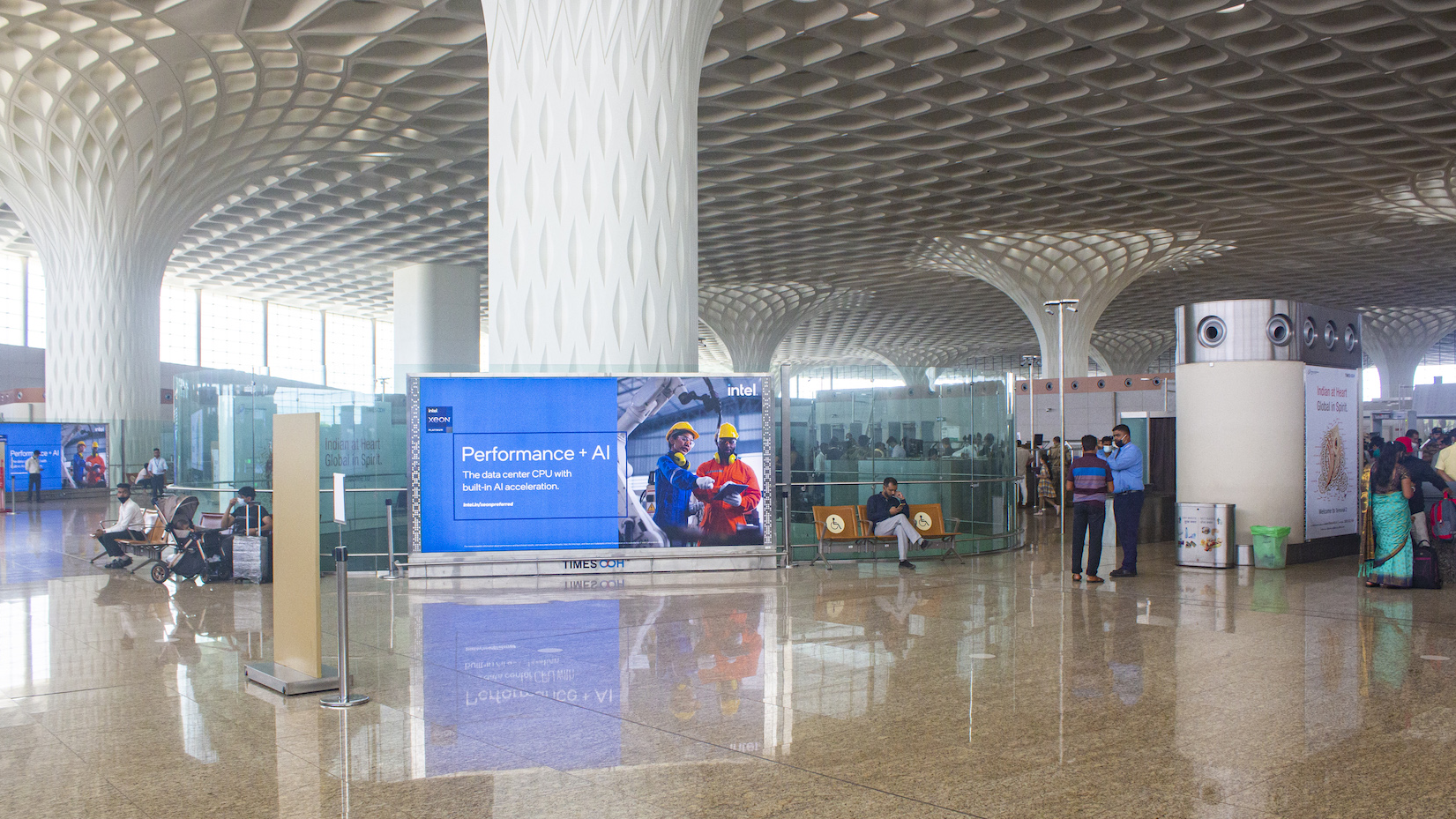 Modern airport terminal interior with a large Intel “Performance + AI” digital advertising display placed in the passenger waiting area.