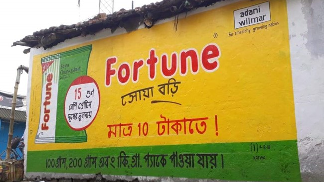Hand-painted wall advertisement for Fortune cooking oil by Adani Wilmar on the exterior wall of a small building.