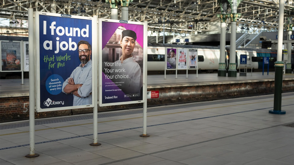 Advertising posters for CV Library and Indeed Flex placed on a railway station platform with a train visible in the background.