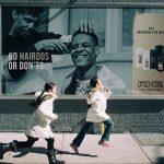 Street billboard advertisement by Axe featuring men’s grooming products with “No Hairdos or Don’ts” tagline and children running past urban wall