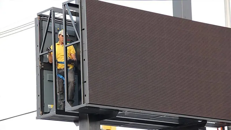 Technician installing or maintaining outdoor billboard structure highlighting execution and compliance in OOH advertising