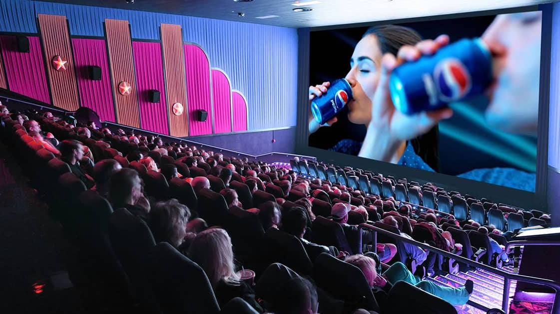 Cinema hall with audience watching a large screen advertisement featuring a beverage brand