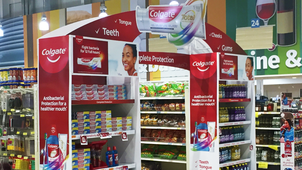 Retail store display featuring Colgate branding with shelves of products and promotional stand