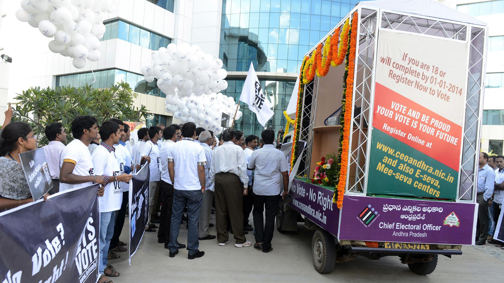 Mobile van used for voter awareness campaign in Andhra Pradesh, with large signage encouraging voter registration and a crowd gathered around.