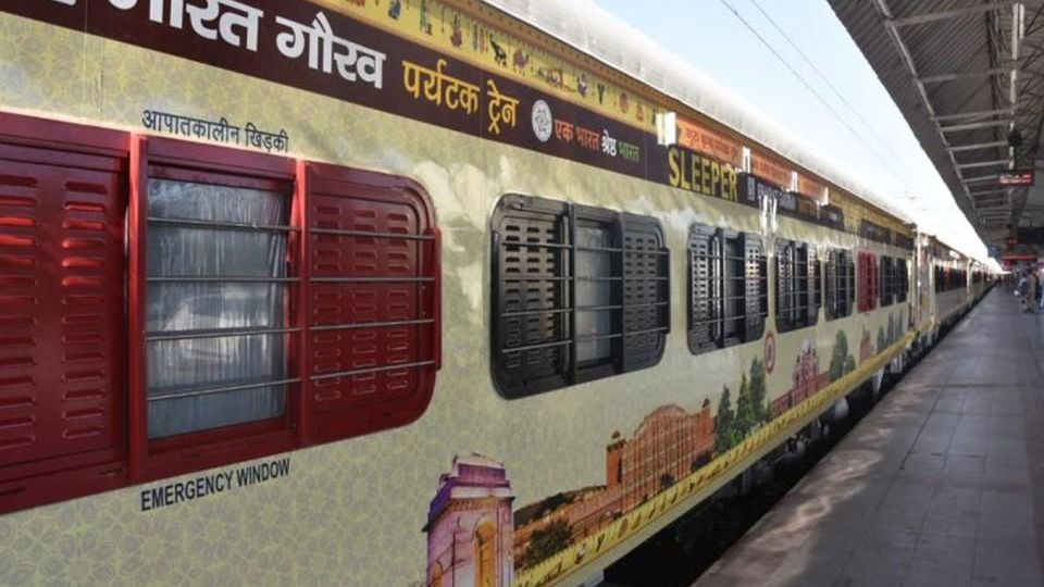 Branded Indian Railways train promoting Bharat Gaurav tourist service, wrapped with cultural visuals and Hindi text at a railway platform.