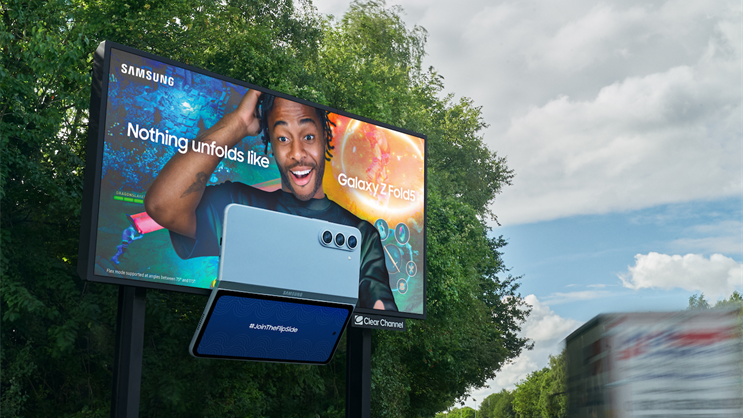 A creative outdoor 3D billboard for the Samsung Galaxy Z Fold5. The ad features a man looking surprised, with a physical-looking model of the folding phone extending outward from the screen.