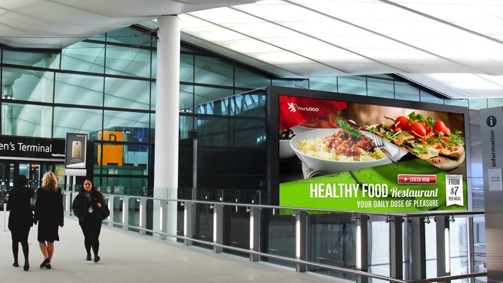 Airport digital billboard advertising in terminal walkway Digital advertising screen inside airport terminal promoting restaurant brand to travelers
