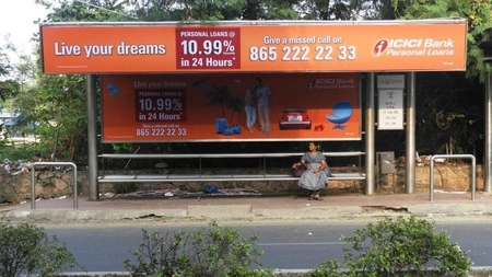Bus stop shelter advertisement by ICICI Bank promoting personal loans with interest rate and contact details