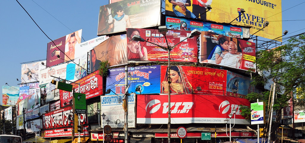 Multiple outdoor billboards and hoardings at a busy urban intersection in India showcasing diverse brand advertisements and high visibility outdoor media