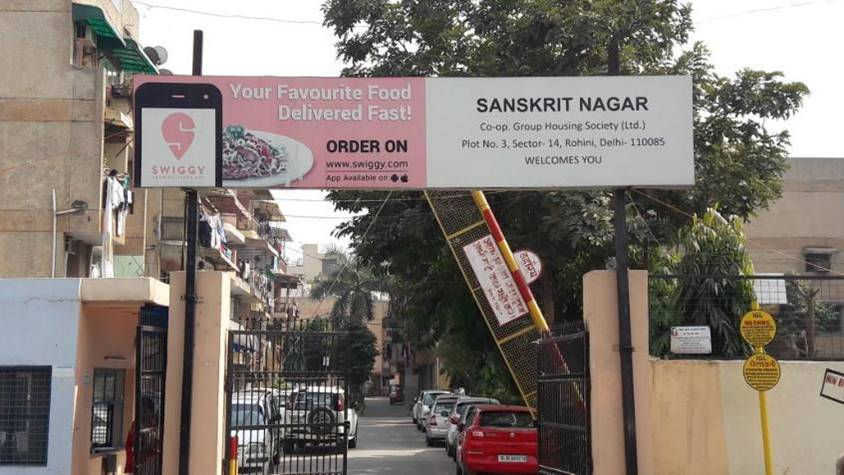 Swiggy outdoor advertising at residential society gate for food delivery Residential society entrance gate featuring Swiggy advertisement promoting fast food delivery service