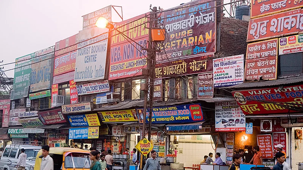 Dense outdoor advertising and signage in Indian market street environment Busy Indian market street filled with multiple shop signboards and hoardings promoting restaurants travel and local services