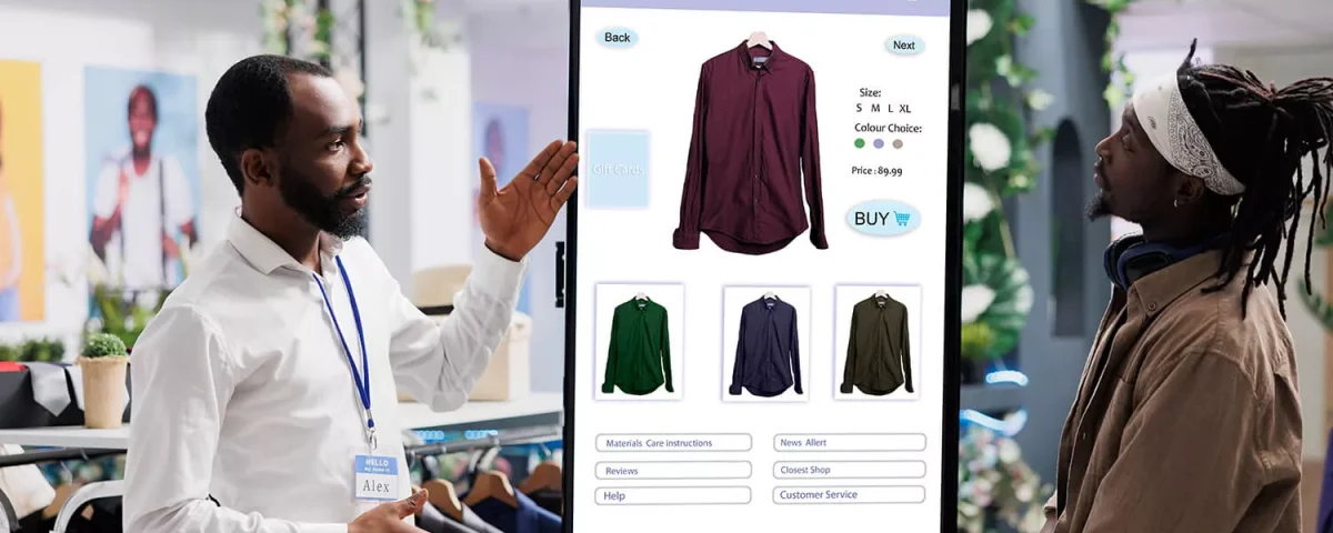 Retail Interactive Kiosk: A store associate demonstrates a large touch-screen vertical kiosk that allows customers to browse apparel, select colors/sizes, and make purchases directly from the shop floor.