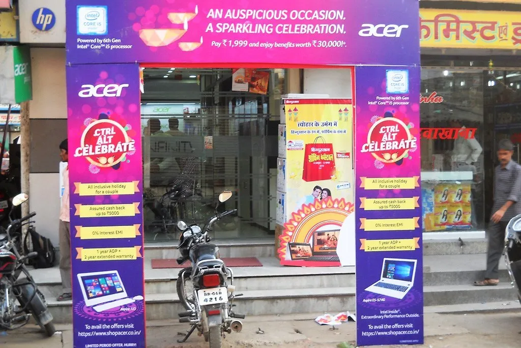 An Acer branded entrance arch frames the entrance of a retail electronics store, promoting festive season offers and product benefits. The storefront activation transforms the shop entrance into a high visibility branding zone, attracting footfall and enhancing the in store customer experience.