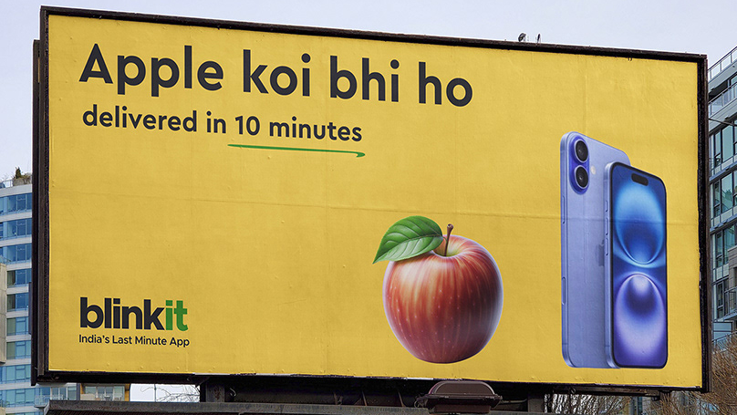 A real-world example of meme marketing through an outdoor billboard for Blinkit. The ad uses a play on words with the phrase "Apple koi bhi ho, delivered in 10 minutes," showing both a physical apple fruit and an Apple iPhone to emphasize their 10-minute delivery promise.